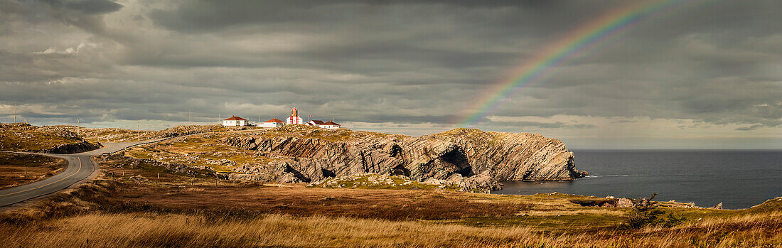 A rainbow across the storm clouds and over the Atlantic ocean and coastline of Newfoundland; Newfoundland, Canada