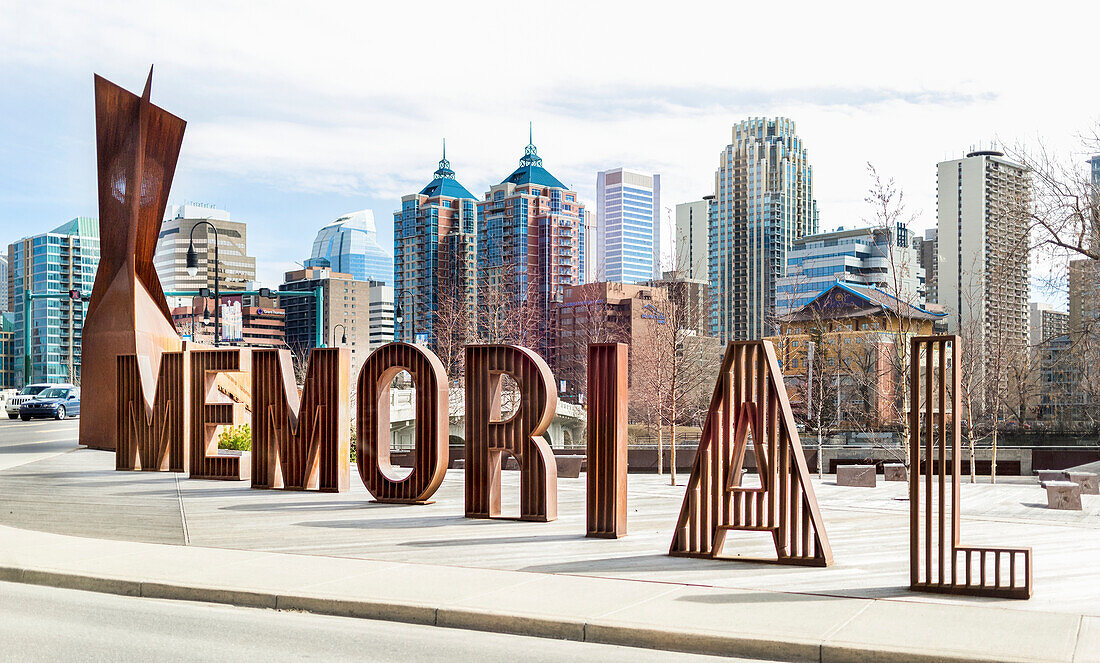 A sign spelled in lettering for Memorial Drive with the Calgary skyline in the background; Calgary, Alberta, Canada