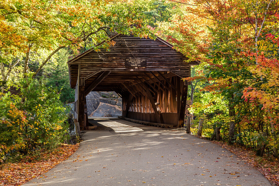 A covered bridge on a back country road in autumn, White Mountains National Forest; New England, United States of America