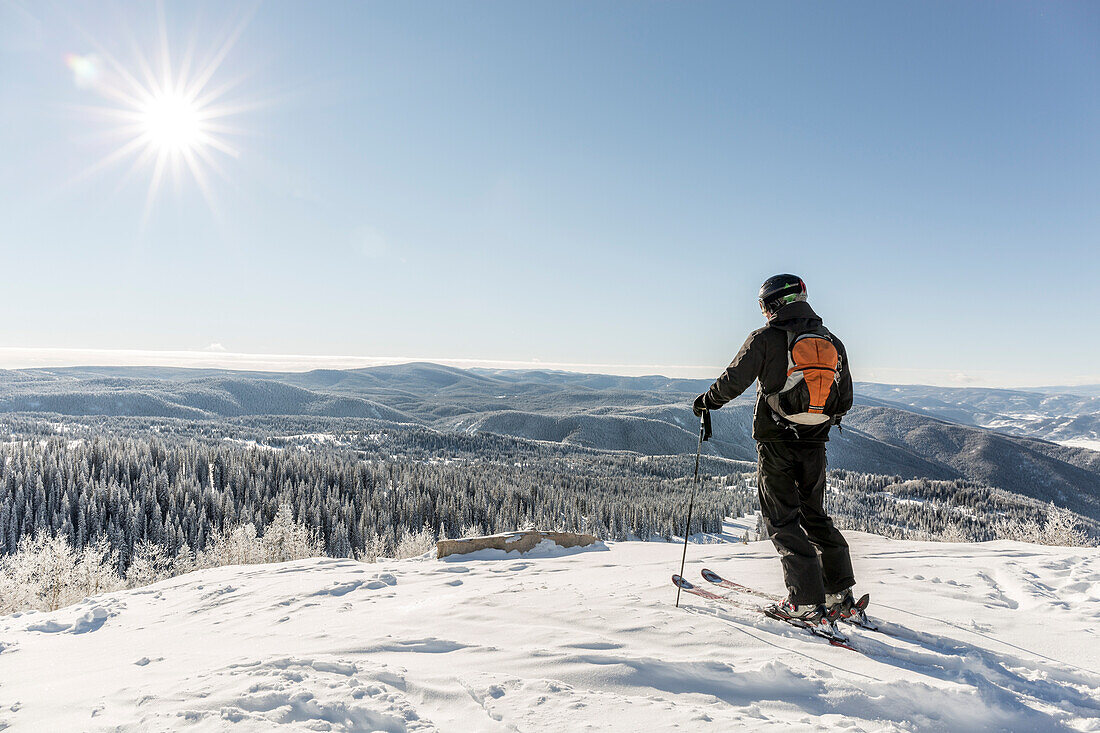 Skier looking over view from summit of Storm Peak in Steamboat Springs, Colorado, USA