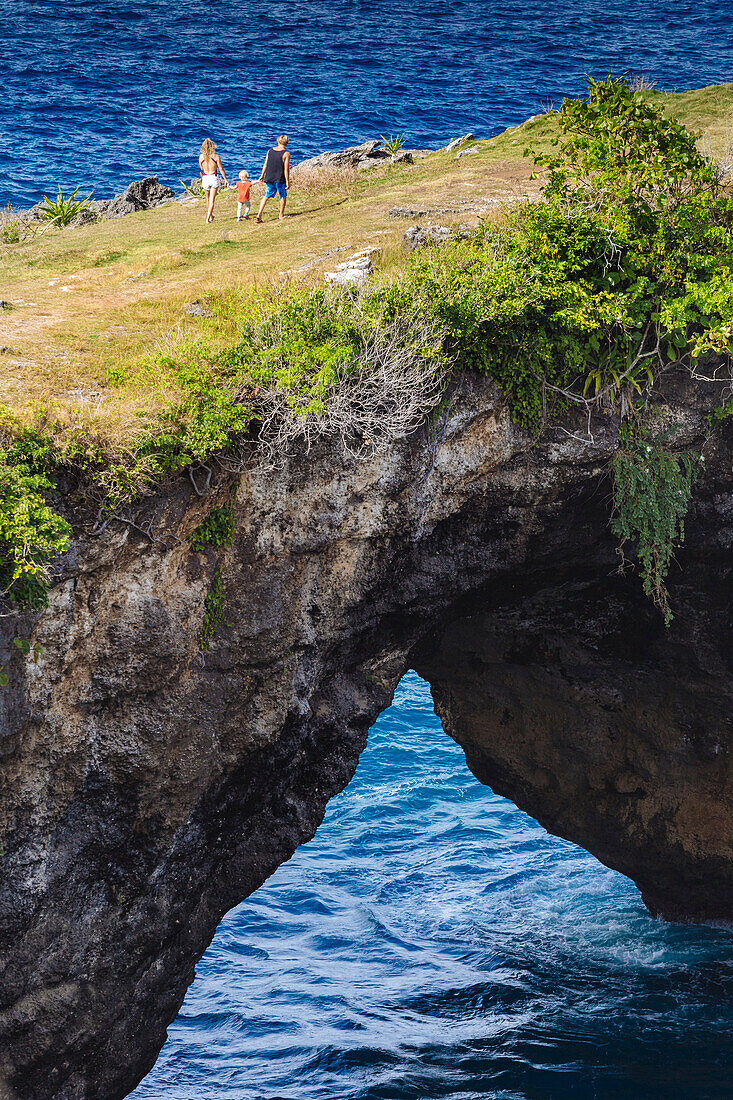 Family walking across coastal arch, Nusa Penida island, Bali, Indonesia