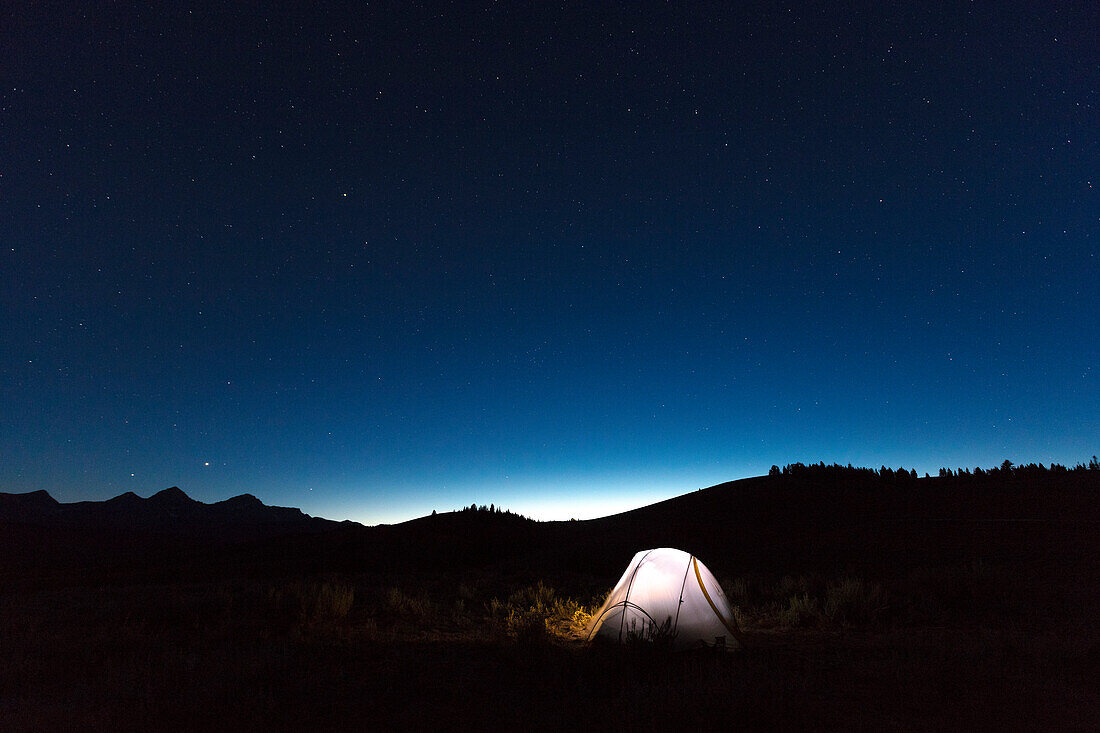Illuminated tent under starry sky at night, Sawtooth Wilderness foothills, Stanley, Idaho, USA