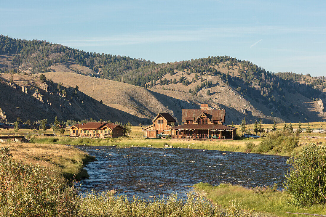 Old farmhouse on bank of Salmon River with Sawtooth Wilderness foothills in background, Stanley, Idaho, USA