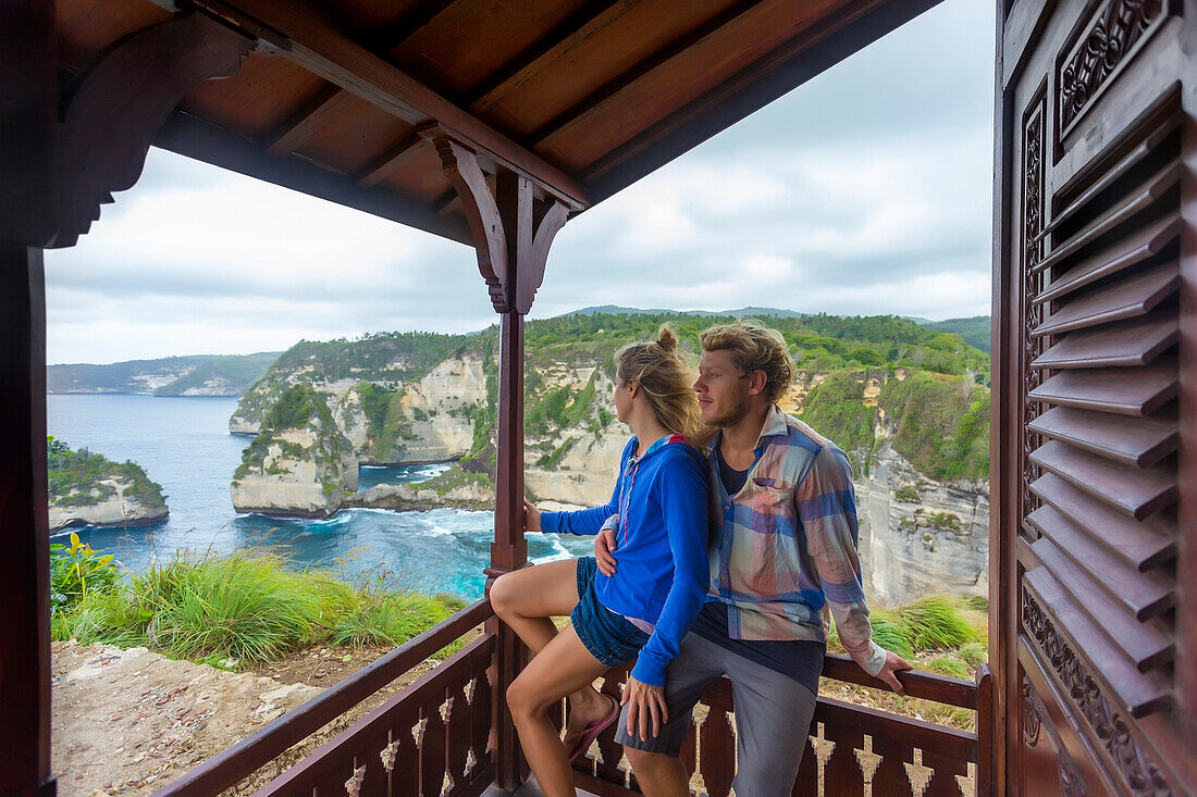 Couple on vacations looking at view of ocean from oceanside hut, Nusa Penida, Bali, Indonesia