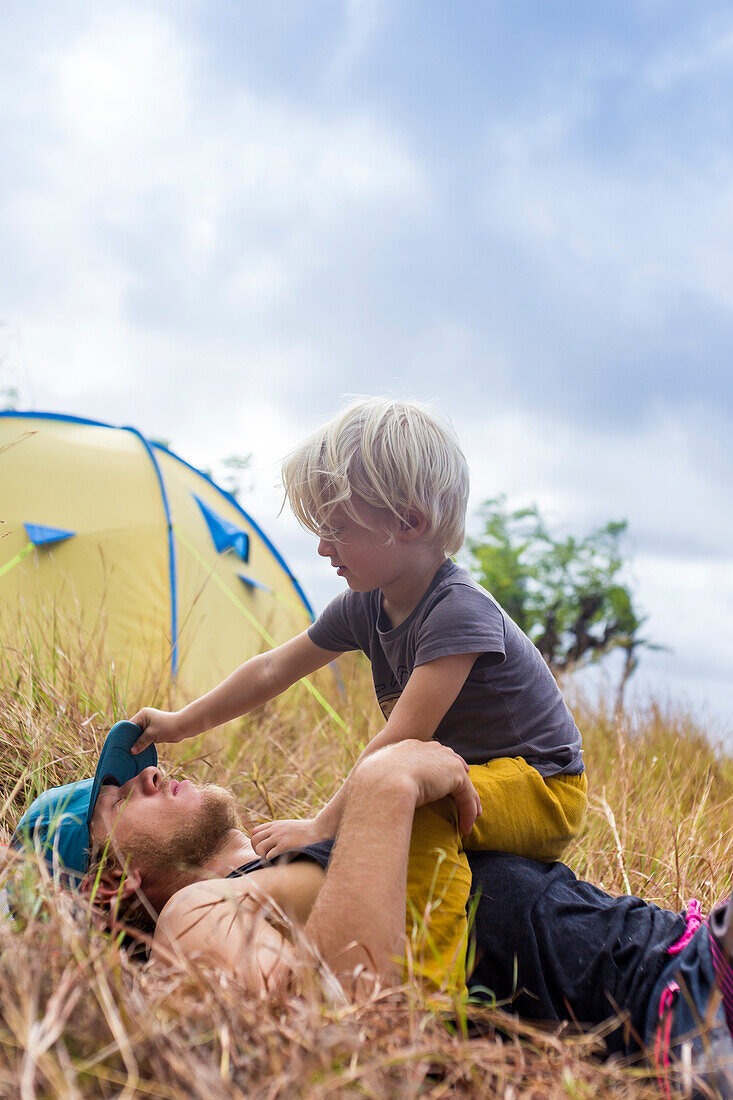 Father and son playing outside tent in meadow, Nusa Penida, Bali, Indonesia