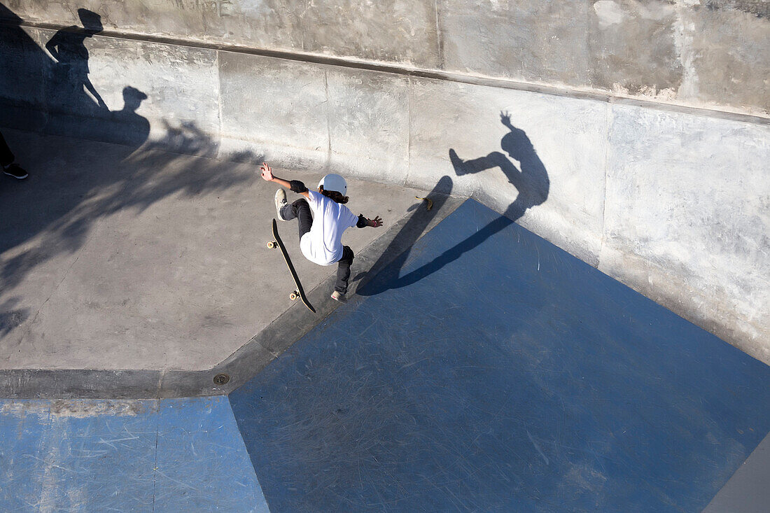 View from above of teenage boy doing kickflip while skateboarding in skate park, Canggu, Bali, Indonesia