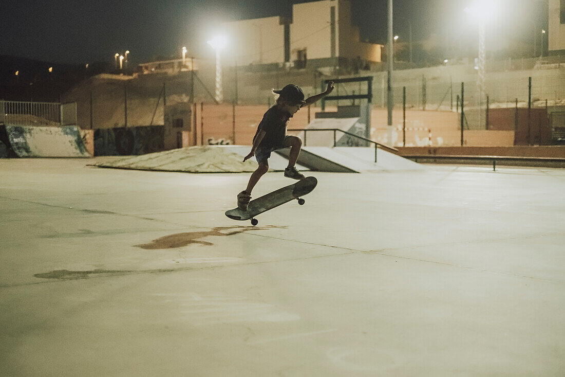 Young skateboarder doing kickflip in skate park at night, Tenerife, Canary Islands, Spain