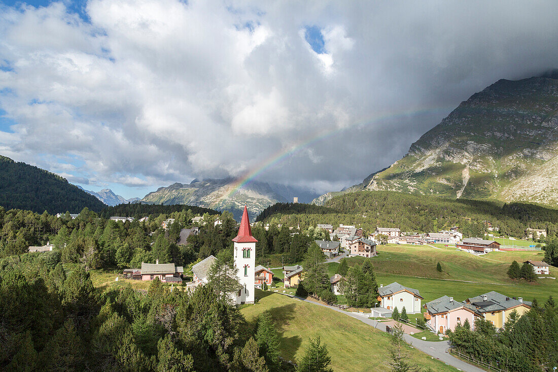 Rainbow over Chiesa Bianca and the village of Maloja, Bregaglia Valley, Engadine, Canton of Graubunden (Grisons), Switzerland, Europe