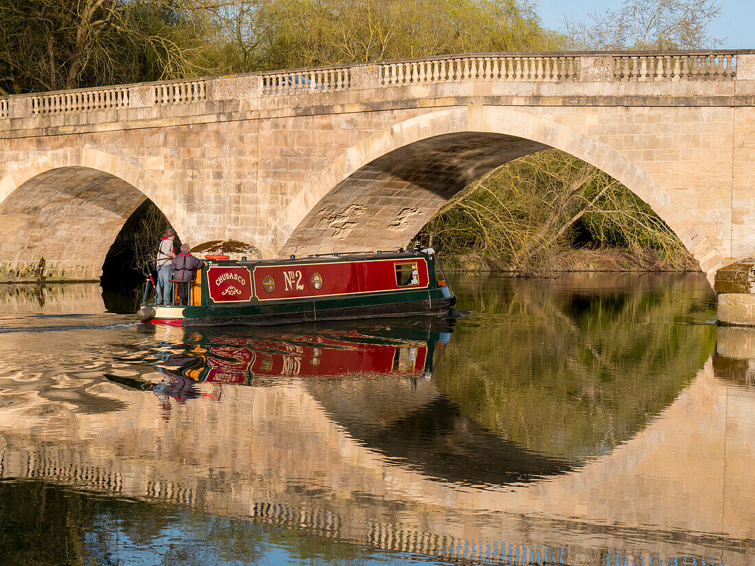Red narrow boat passes under Shillingford Bridge reflected in River Thames, Shillingford, Oxfordshire, England, United Kingdom, Europe