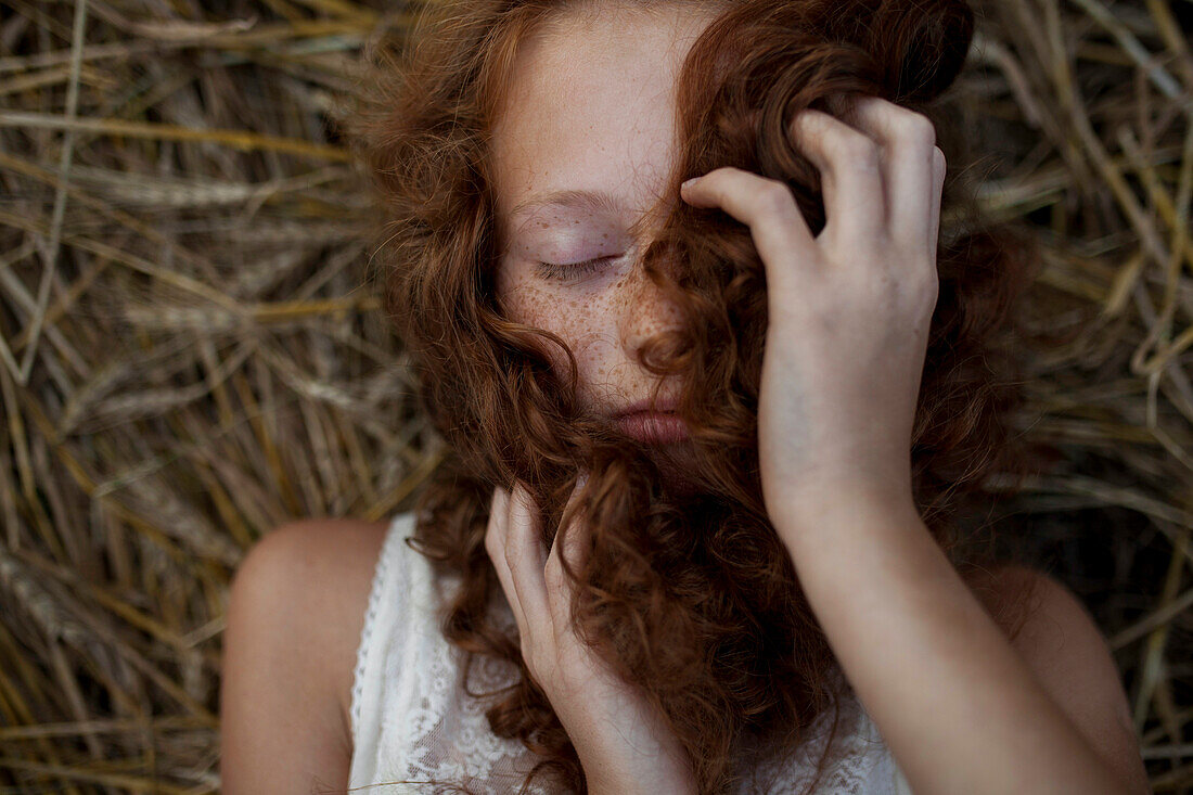Caucasian girl laying in wheat holding hair