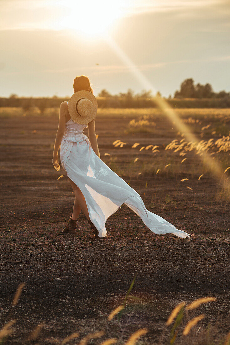 Sexy kaukasische Frau in weißem Kleid beim Spaziergang im Feld