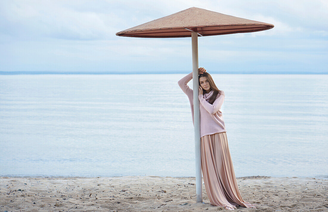 Nachdenkliche kaukasische Frau lehnt sich an einen Sonnenschirm