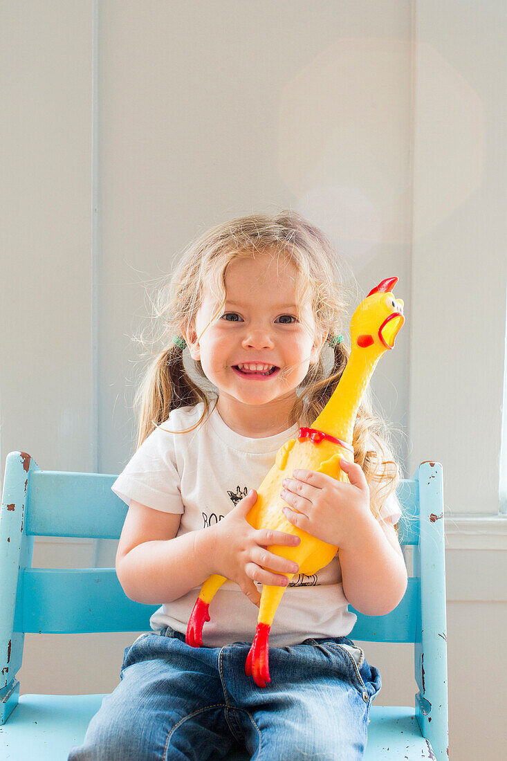 Smiling Caucasian girl holding rubber chicken