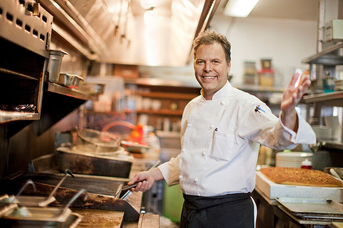 Portrait of Caucasian chef waving in restaurant kitchen