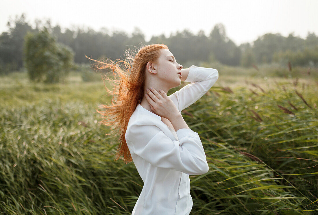 Wind blowing hair of Caucasian woman in field