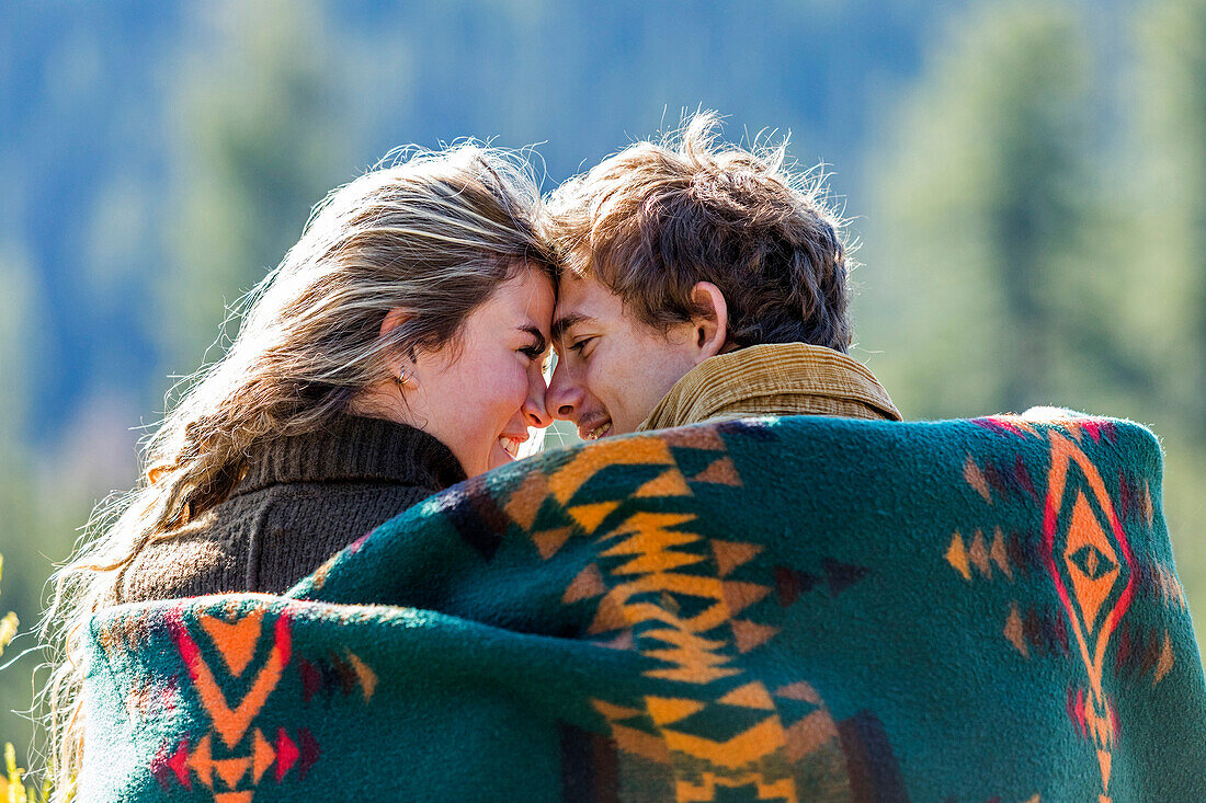 Caucasian couple wrapped in blanket rubbing noses