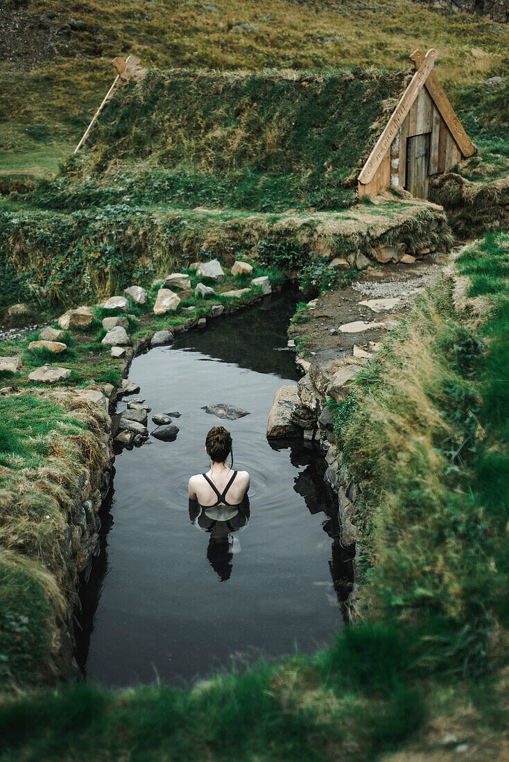 Caucasian woman swimming in pond near rural house