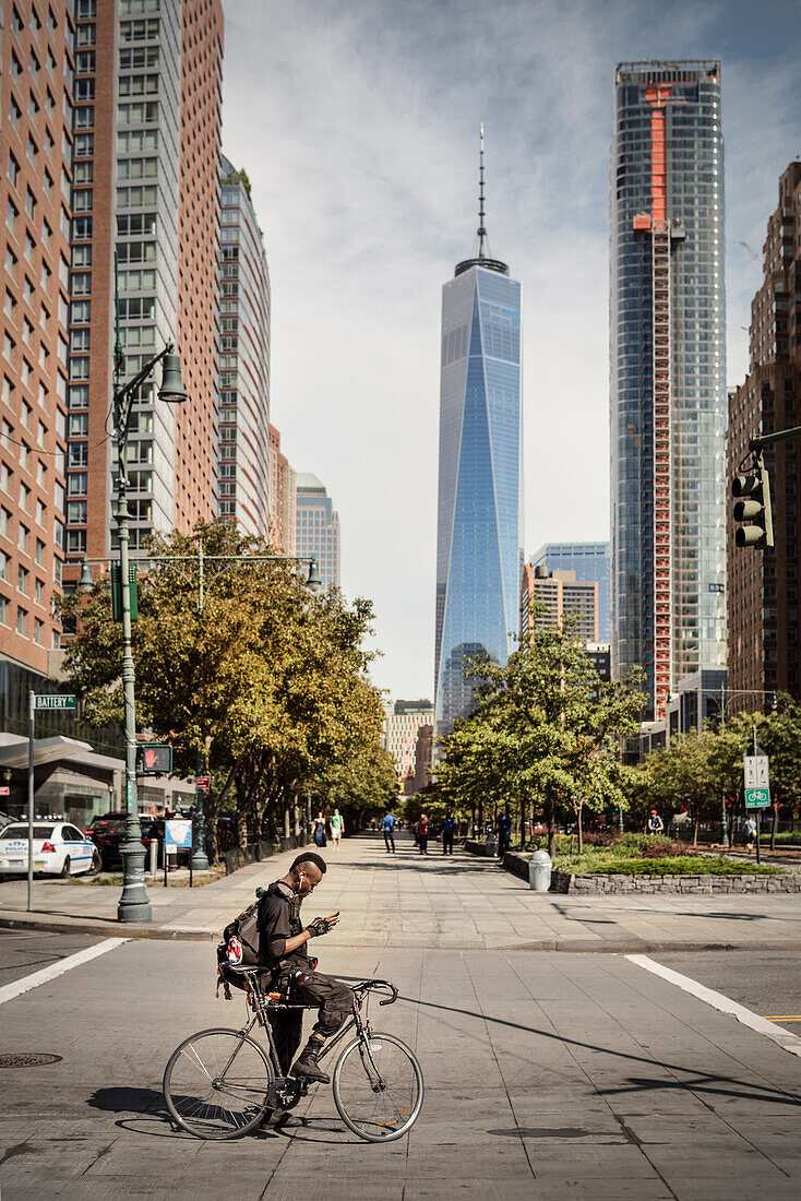 stylish New Yorker with Iroquois sitting on a racing bike in front of ONE World Trade Center and looking at mobile phone, Manhattan, NYC, New York City, United States of America, USA, North America