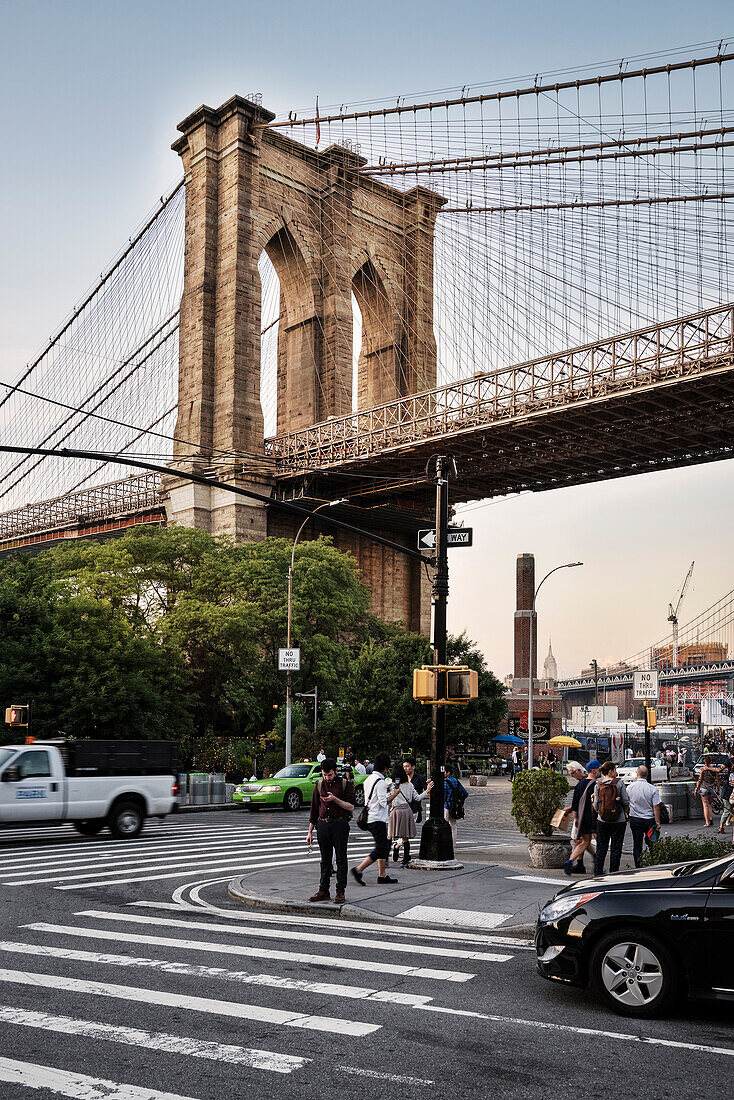 pedestrian looking at a mobile phone at a zebra crossing, in front of Brooklyn Bridge, Brooklyn, NYC, New York City, United States of America, USA, North America