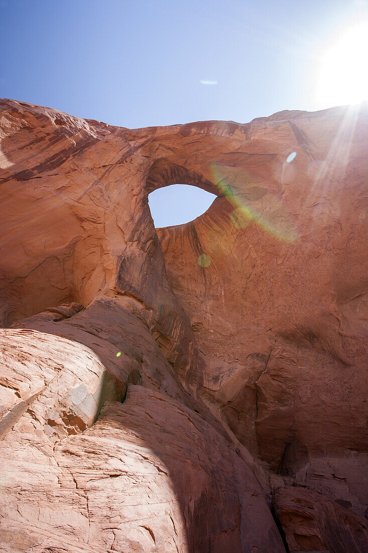 In a remote back country location in Monument Valley, a hole in the sandstone resembles an eye and is called Sun's Eye, as the sun shines brightly behind.