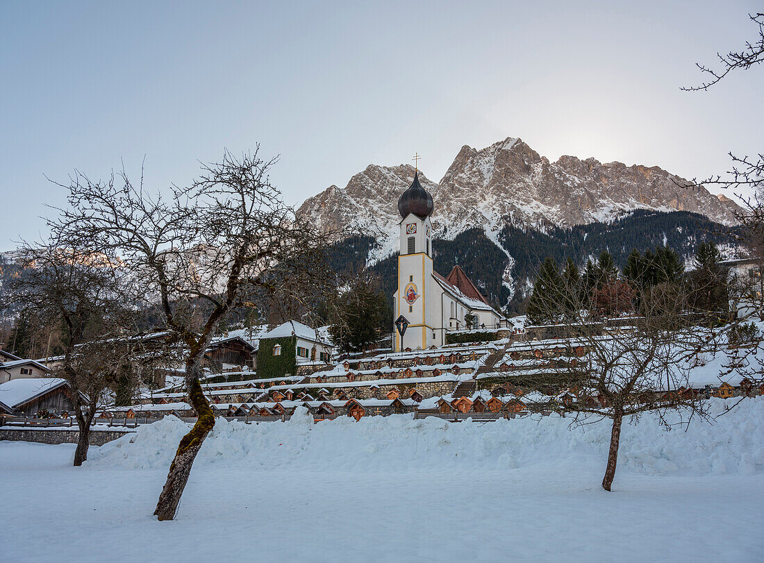 Blick auf den verschneiten Friedhof und die Pfarrkirche St. Johannes der Täufer vor dem Großen Waxenstein, Grainau, Oberbayern, Deutschland