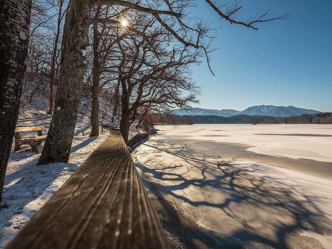 Light and shadow on the frozen Staffelsee, in the background the foothills of the Ammergau Alps, Seehausen, Upper Bavaria, Germany