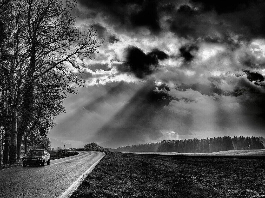 A Ford Capri crosses an atmospheric landscape in Chiemgau, Gstadt am Chiemsee, Upper Bavaria, Germany
