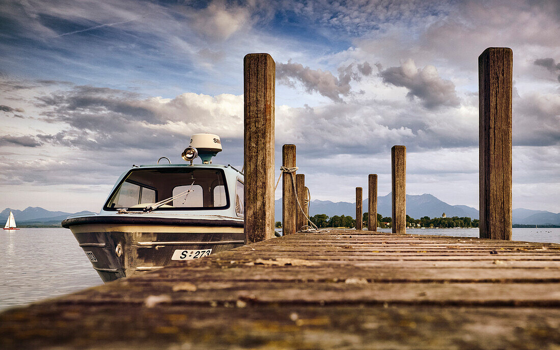 View of a boat on a jetty, in the background the Fraueninsel and the Chiemgau Alps on a summer evening, Gstadt am Chiemsee, Upper Bavaria, Germany