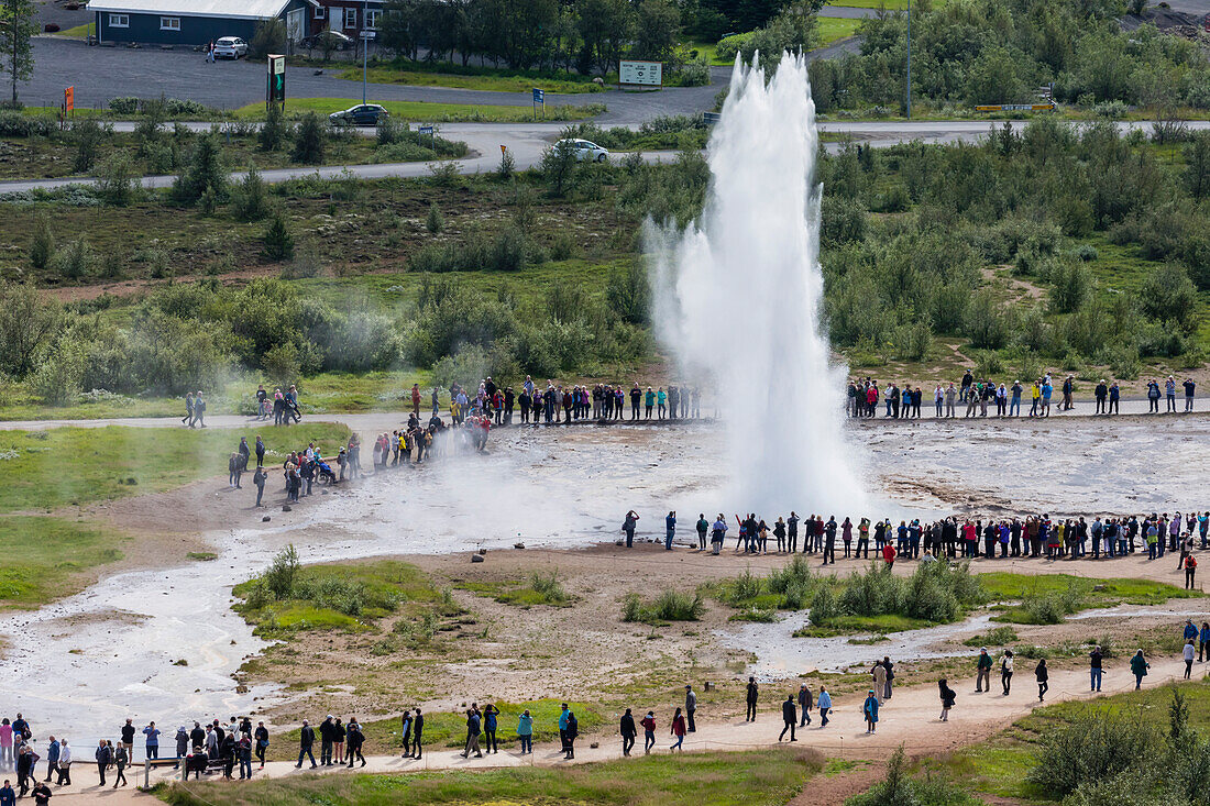 Tourists watch the eruption of the Strokkur geyser, Haukadalur valley, Hvita River, Iceland, Polar Regions