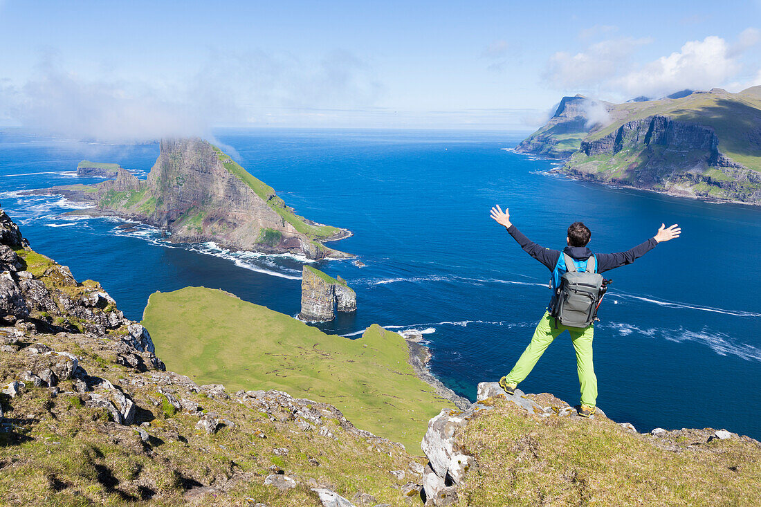 Man on cliffs looks towards Drangarnir rock, Vagar Island, Faroe Island, Denmark, Europe