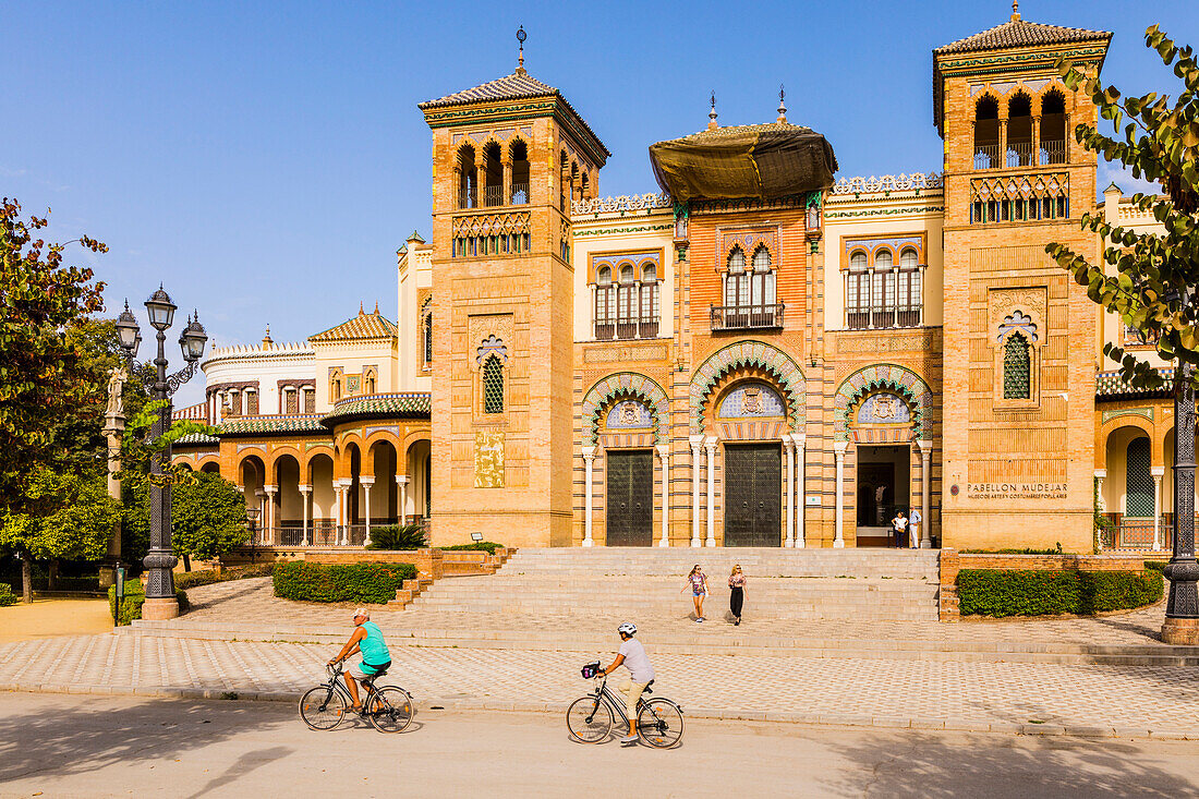 People riding bikes in front of the Museum of Popular Arts and Traditions in Maria Luisa Park, Seville, Andalusia, Spain, Europe