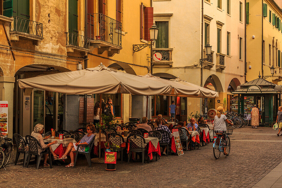 View of cyclist, pedestrians and cafe on cobbled street of Via Roma, Padua, Veneto, Italy, Europe