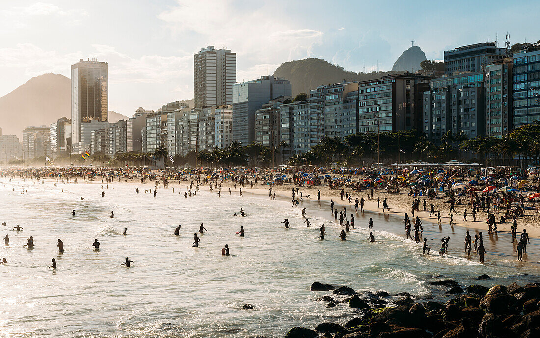 Crowded Copacabana Beach with distant view of Christ the Redeemer statue far right, Rio de Janeiro, Brazil, South America