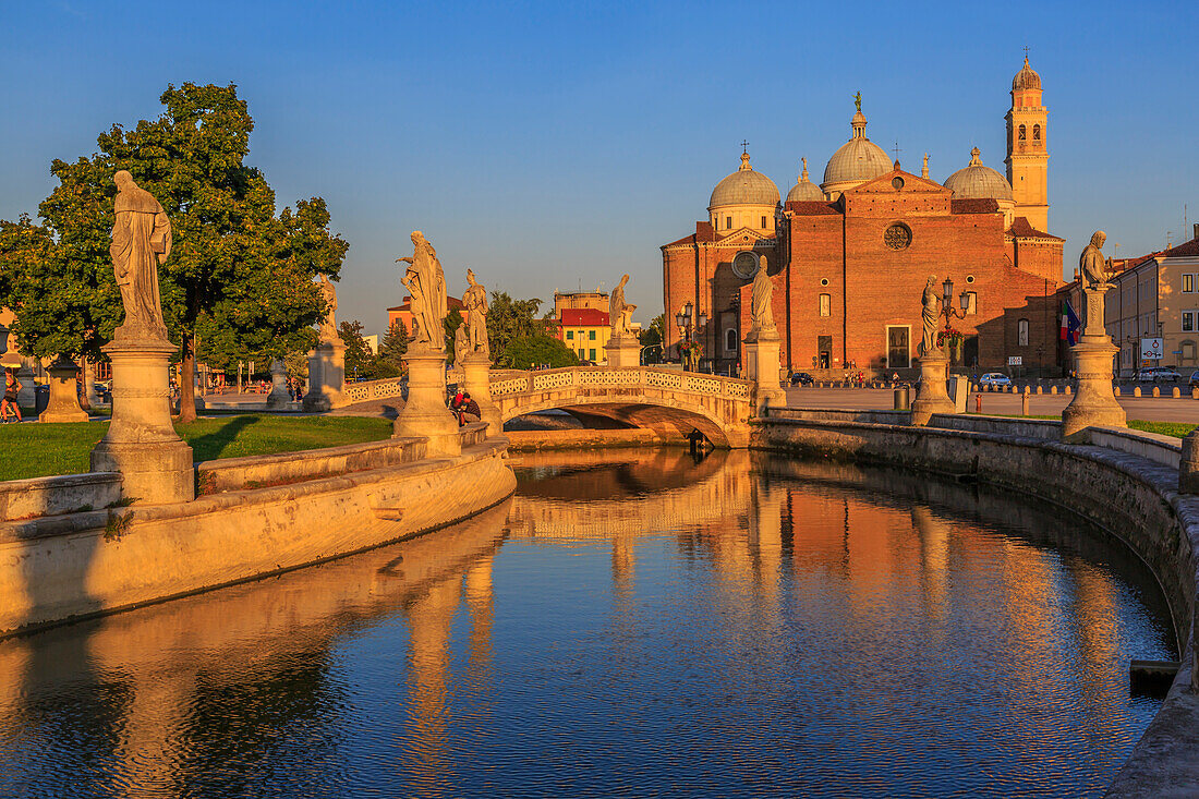 View of statues in Prato della Valle during golden hour and Santa Giustina Basilica visible in background, Padua, Veneto, Italy, Europe