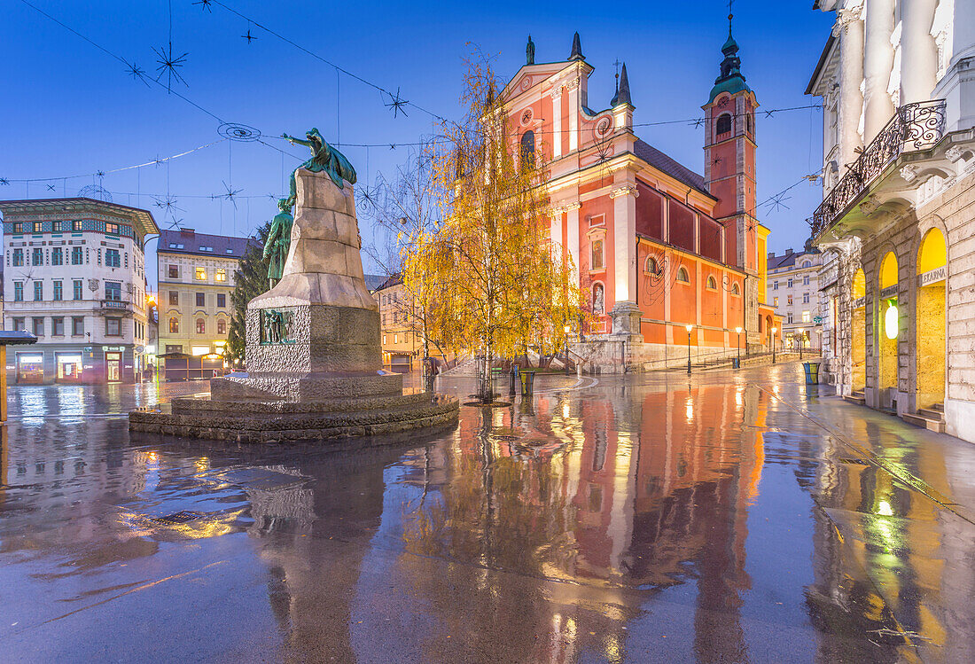 Reflections of the ornate facade of the Franciscan Church of the Annunciation and Preseren Monument in Plaza Presernov at dusk, Ljubljana, Slovenia, Europe