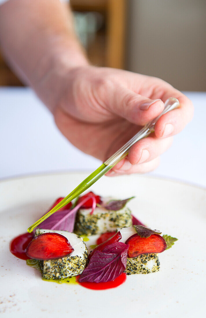 Chef puts finishing touches to sashimi swordfish with plums