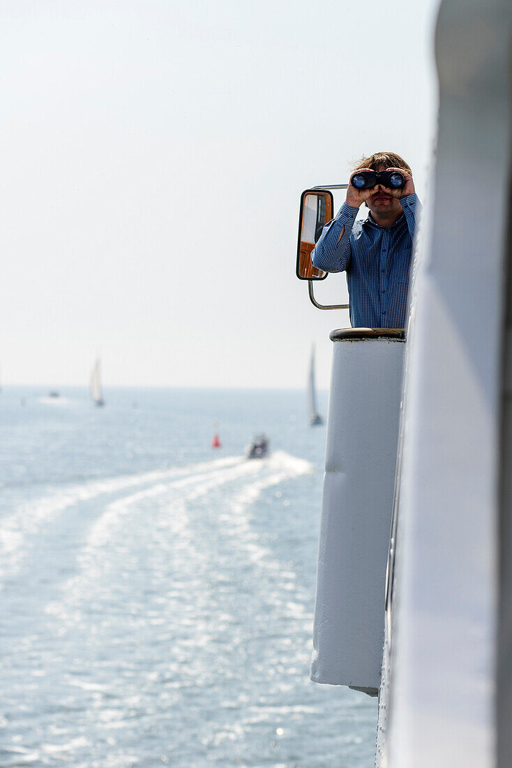 Captain with binoculars on ferry between Vitte and Schaprode, Hiddensee, Ruegen, Baltic Sea coast, Mecklenburg-Vorpommern, Germany
