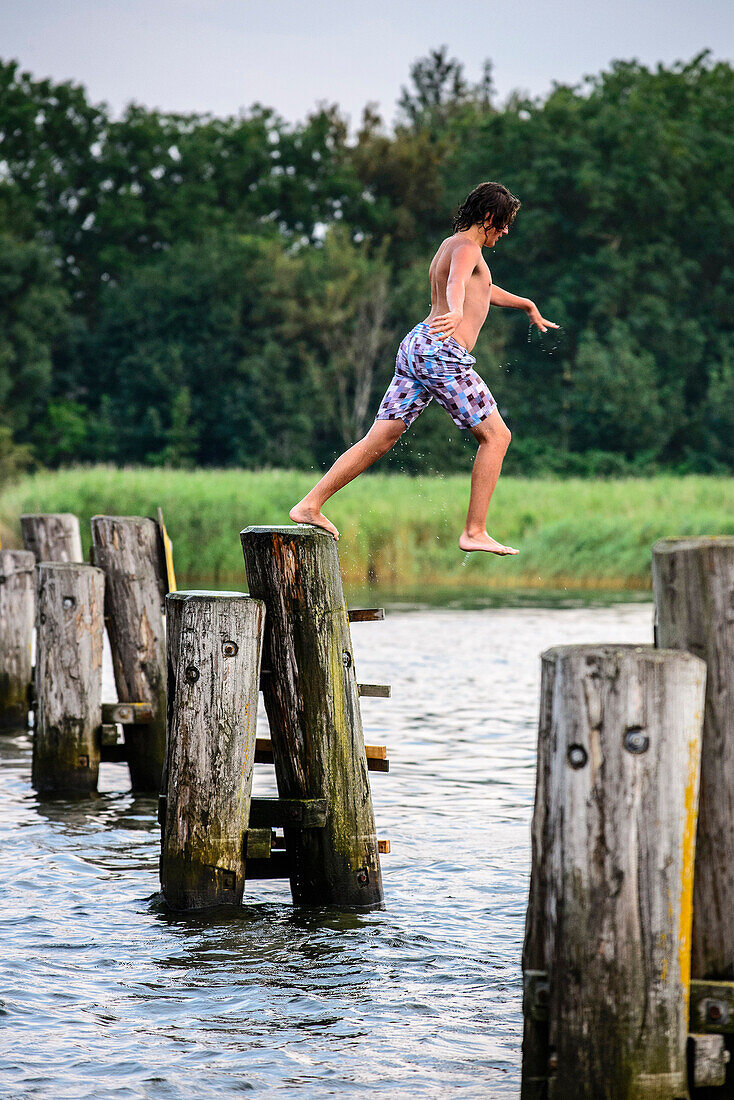 Boy jumps into water in Waase village on Ummanz, Ruegen, Baltic Sea coast, Mecklenburg-Vorpommern, Germany