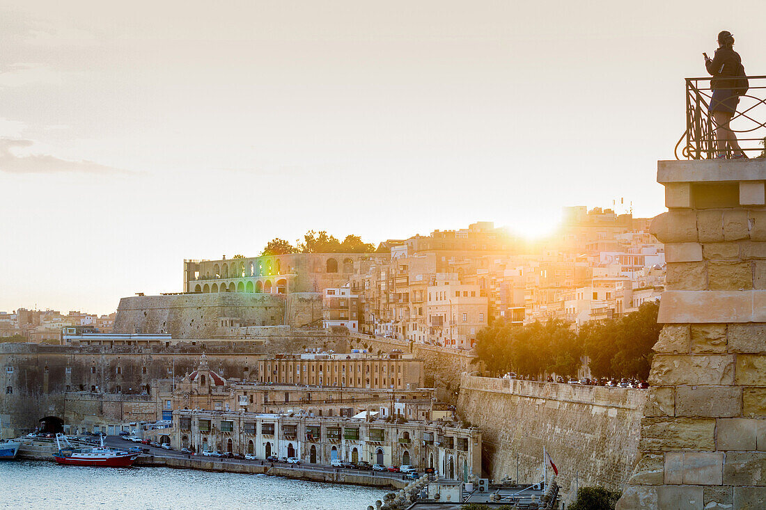 Person photographing the Grand Harbour in Valletta at dusk. Valletta, Malta, Mediterranean, Europe