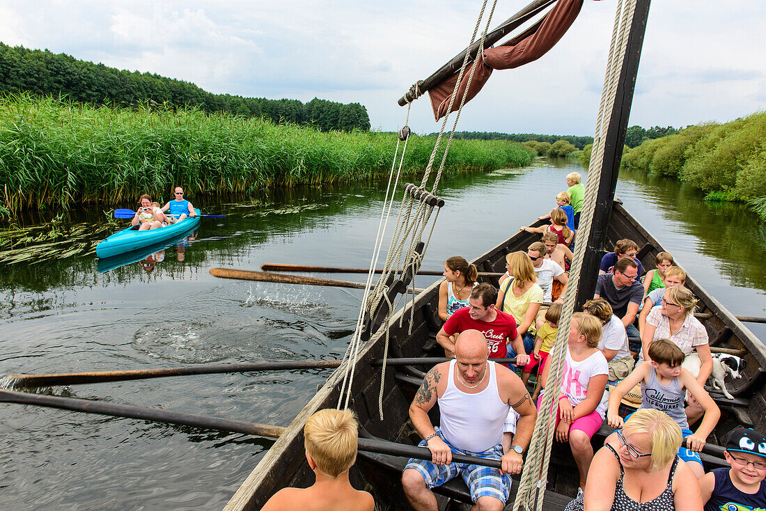 Touristen rudern in einem historischen Holzboot im Freilichtmuseum Ukranenland in Torglow, Ostseeküste, Mecklenburg-Vorpommern, Deutschland