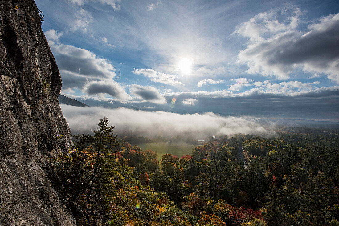 Early morning fog covering the bright fall foliage of New Hampshire as seen from Humphrey's Ledge in North Conway, New Hampshire.