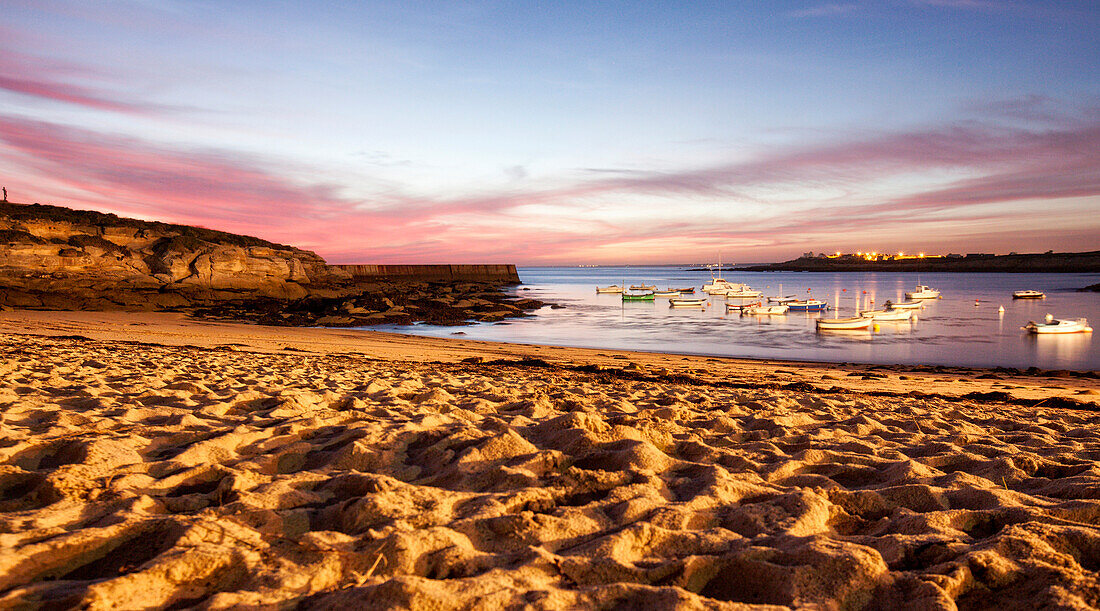 Beach at sunset and boats near fishing village of Kerroch, Brittany, France