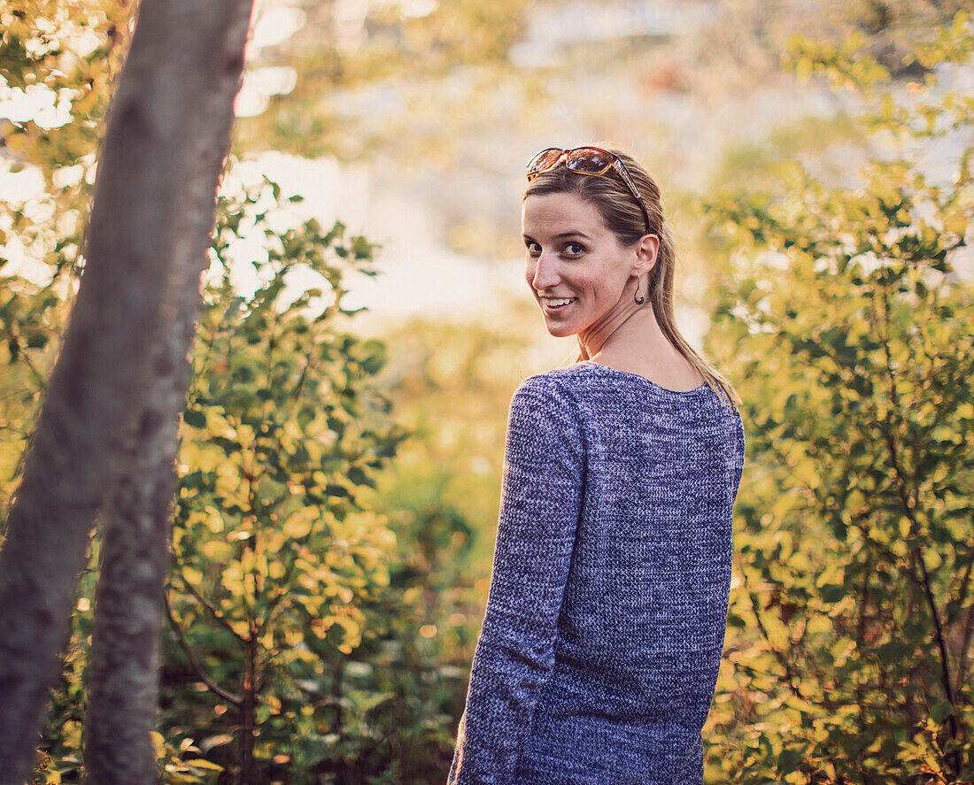 Amy looks back over her shoulder while walking through the woods on an island off the Maine coast