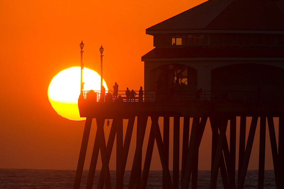 Sun setting behind pier at Huntington Beach, Orange County, California, USA