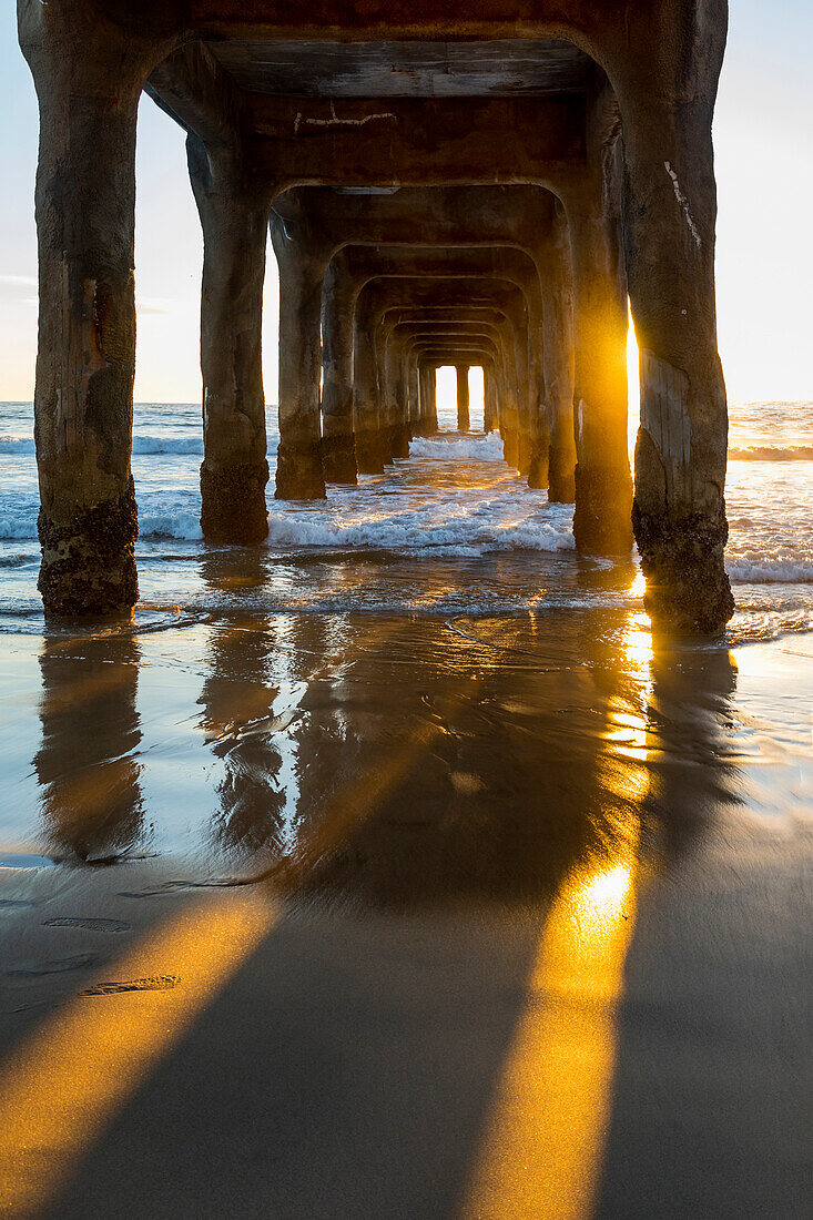 View underneath Manhattan Beach pier at sunset, Los Angeles, California, USA