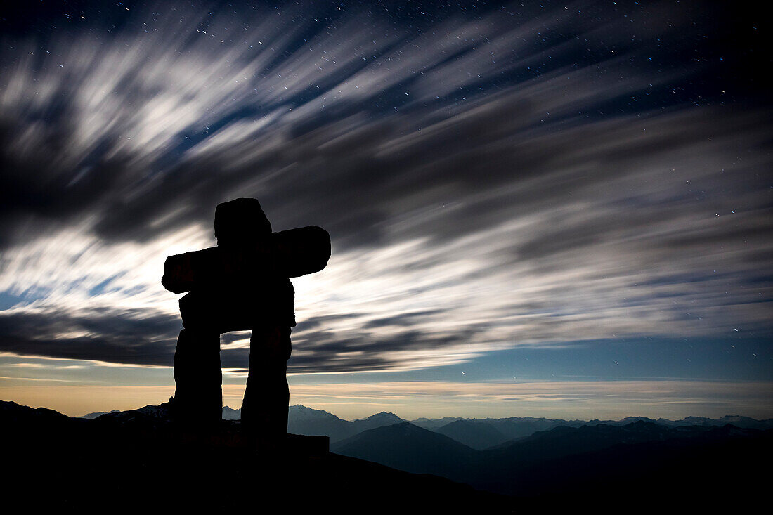 An inuksuk is a human-made stone landmark or cairn used by the Inuit, Inupiat, Kalaallit, Yupik, and other peoples of the Arctic region of North America. Here it is seen at night during a full moon. Whistler, British Columbia, Canada
