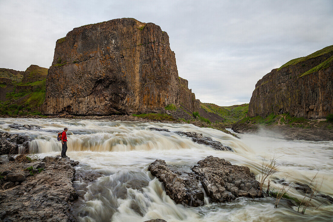 Hiker near river and rock formation in Palouse Falls State Park, Washington State, USA