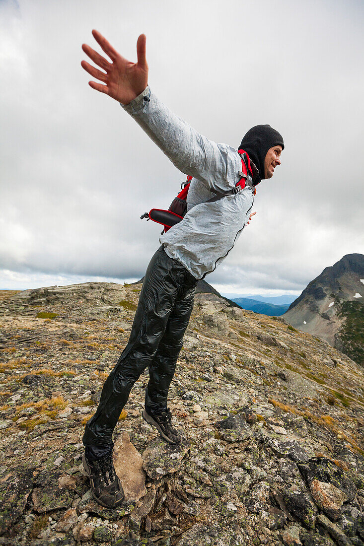 Backpacker throwing body into wind on rocky ridge, Merritt, British Columbia, Canada