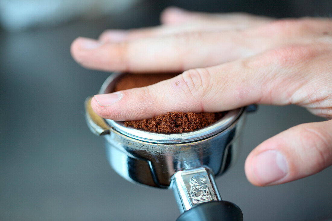 Close up of human hand and handle with ground coffee, Oakland, USA