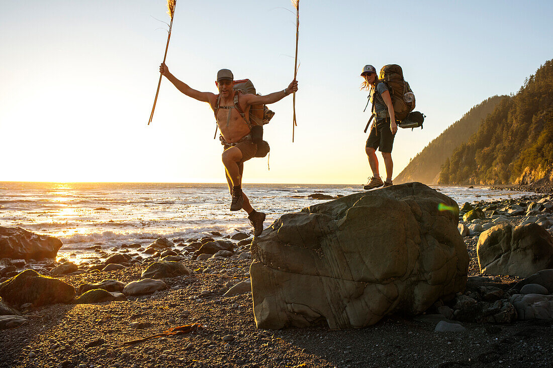 Two backpackers having fun while hiking along beach at sunset, Lost Coast Trail, Kings Range National Conservation Area, California, USA